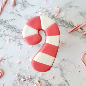 A candy cane shortbread sugar cookie decorated to look like a candy cane.