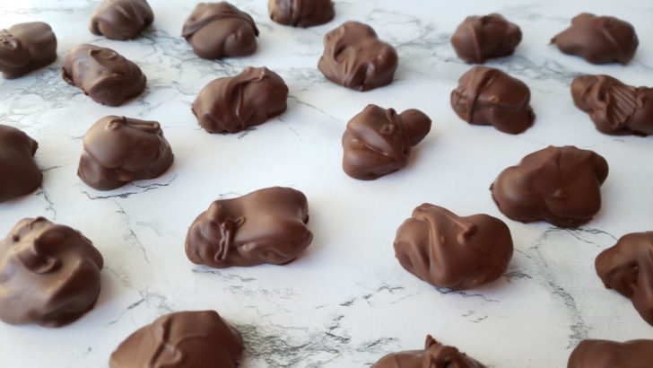 Chocolate covered macadamia nuts on a marble surface.