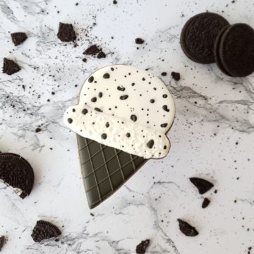 A cookies and cream shortbread sugar cookie decorated to look like a cookies and cream ice cream cone.