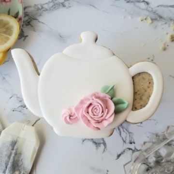 An earl grey shortbread sugar cookie decorated to look like a white teapot.