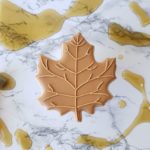A maple shortbread sugar cookie decorated to look like a maple leaf.