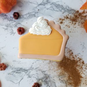 A single pumpkin pie shortbread sugar cookie decorated to look like a slice of pumpkin pie.