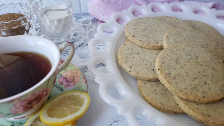 Earl grey shortbread sugar cookies arranges on a plate next to a teacup of earl grey tea. 