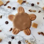 A Pecan turtle shortbread sugar cookie decorated to look like a pecan turtle confection.