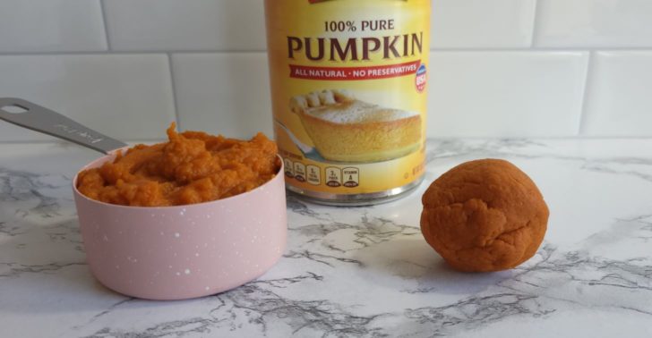 Pumpkin pie puree in a ½ cup measuring cup, next to a ball of pumpkin pie puree that has had moisture squeezed out