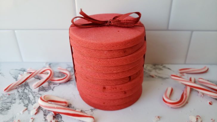 Stacked candy cane shortbread sugar cookies tied with a red ribbon.