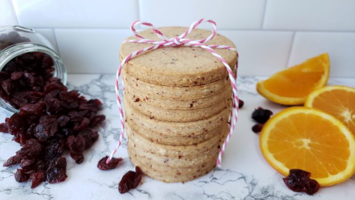 Stacked cranberry orange shortbread sugar cookies tied with a pink and white ribbon. 