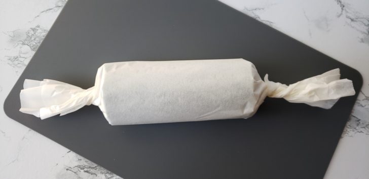 A log of cookie dough wrapped in parchment paper. 