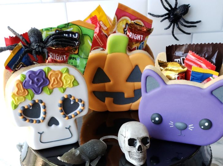 Close up of Halloween treat boxes made out of decorated cookies and filled with candy.