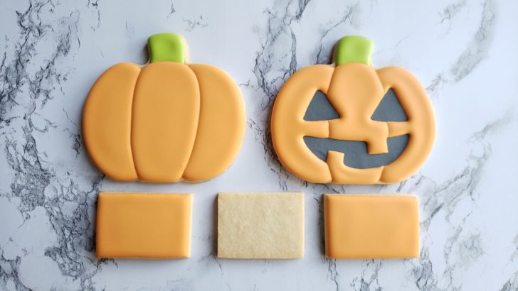 Two decorated jack o' lantern cookies and 3 rectangle cookies. 
