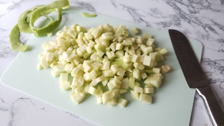 Peeled and diced apple on a cutting board. 