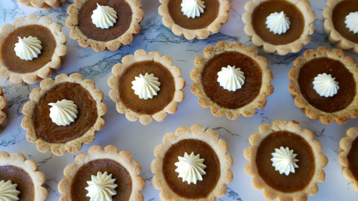 Overhead view of pumpkin pie mini tarts sitting on a marble surface. 