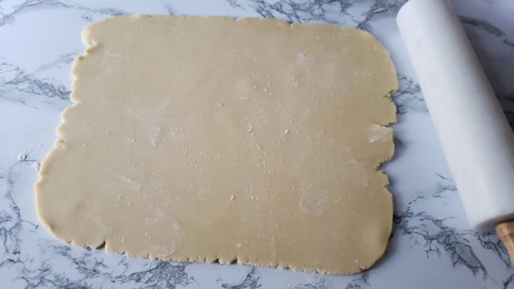 Shortbread sugar cookie dough rolled out on a marble surface. 