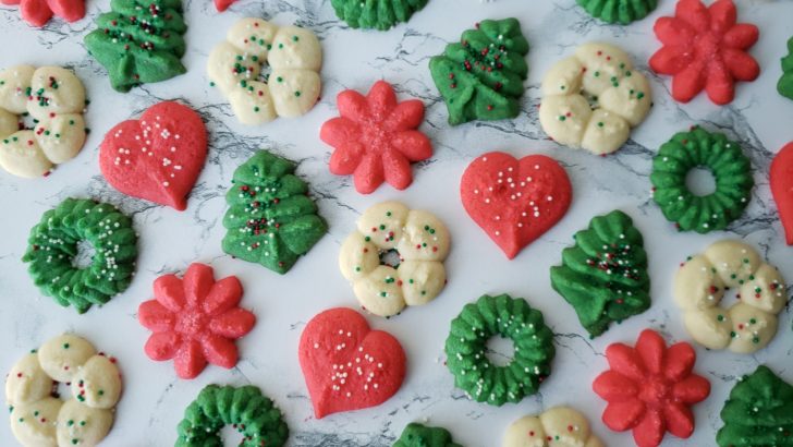 Green, red, and white Christmas spritz cookies on marble surface. 