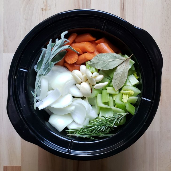 A crockpot filled with ingredients for turkey stock. 